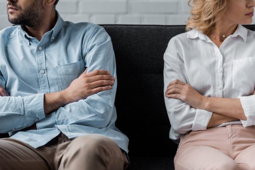 cropped shot of couple sitting on couch after quarrel